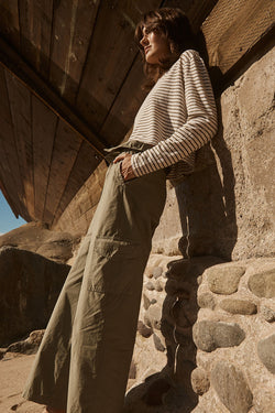 Stateside Fine Poplin Foldover Cargo Pant in Fern-model leaning on a stone wall