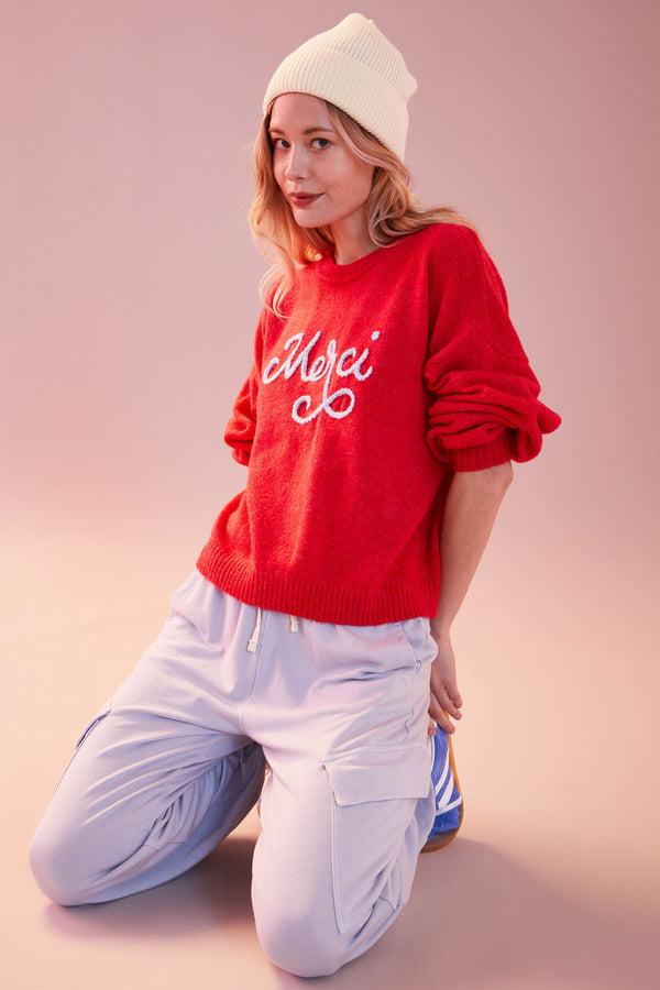 Sundry Merci Crew Neck Sweater in Flare Red-model is kneeing and wearing a white beanie