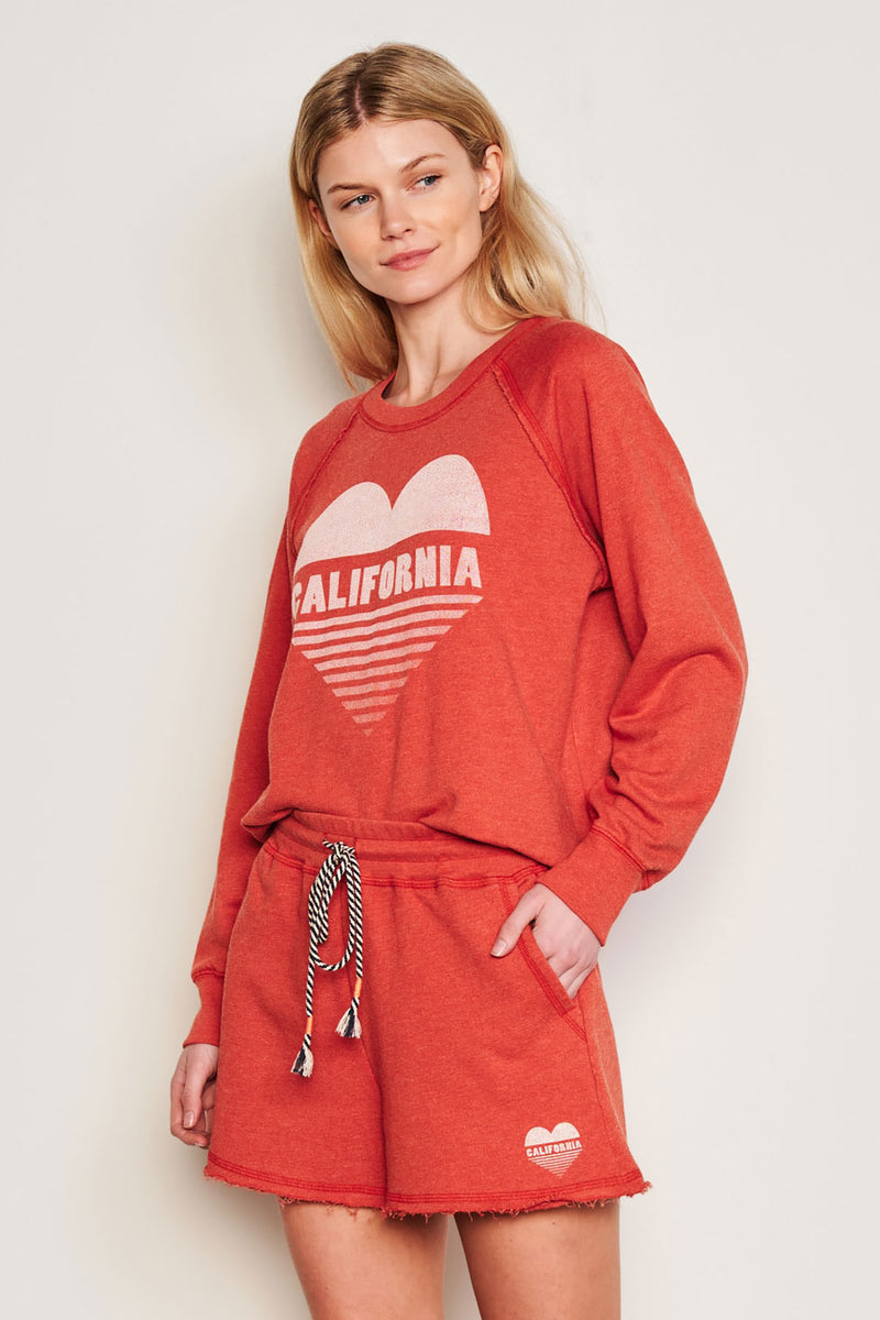 Sundry Cali Heart Raglan Sweatshirt in Burnt Red-side view model has her hands in her pockets