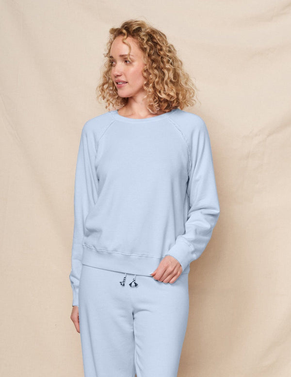 Woman wearing a light blue tracksuit against a beige background